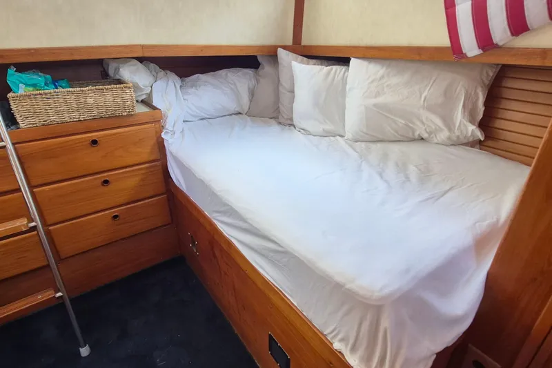 Slide: The Image of Cozy cabin bed in 1990 Sabreline 36 Fast Trawler with wooden drawers and white bedding. - 27