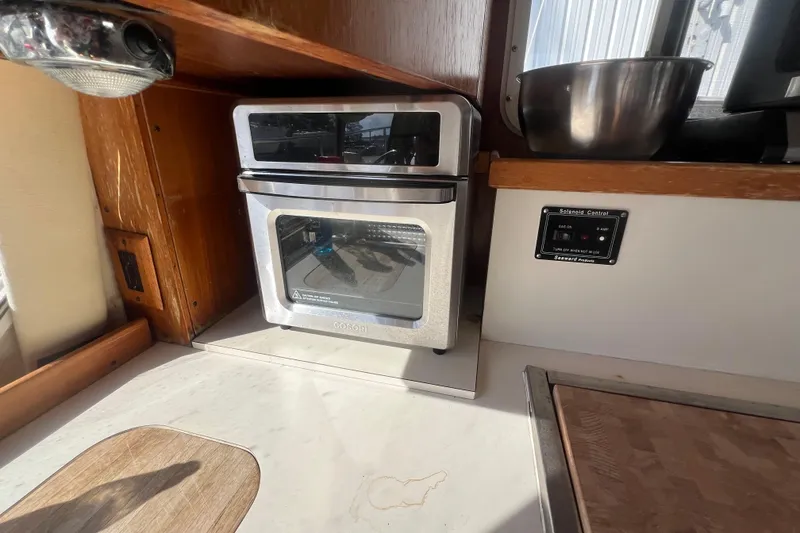 Slide: The Image of Compact kitchen area in a 1990 Sabreline 36 Fast Trawler with a modern oven. - 34