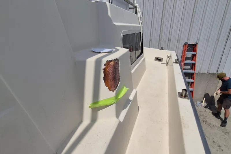 Slide: The Image of 1990 Sabreline 36 Fast Trawler undergoing repair, with visible hull damage and a worker nearby. - 48