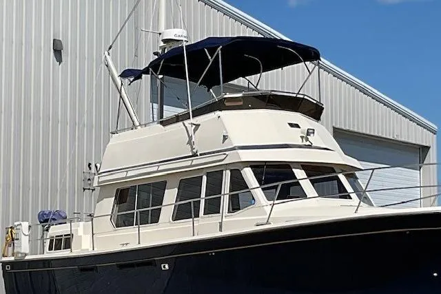 Slide: The Image of 1990 Sabreline 36 Fast Trawler docked near a metal building under a clear blue sky. - 93