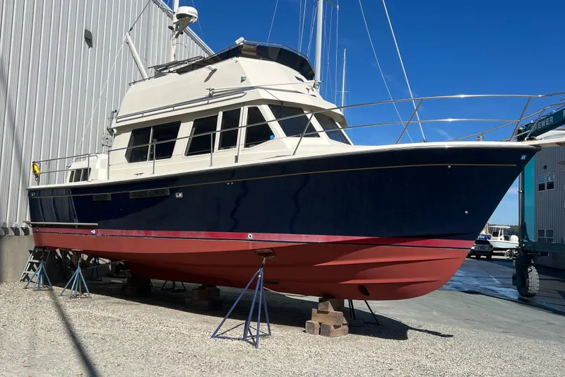 Slide: The Image of 1990 Sabreline 36 Fast Trawler in dry dock, blue and red hull, marina background. - 95