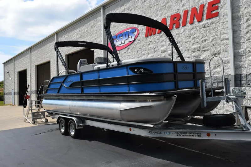 Slide: The Image of 2026 Bentley Pontoons Legacy 243 Swingback on trailer outside marine dealership. - 2