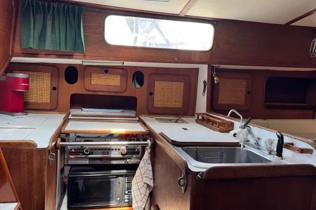 Slide: The Image of 1982 Morgan 383 yacht interior kitchen with stove, sink, and wooden cabinets. - 7