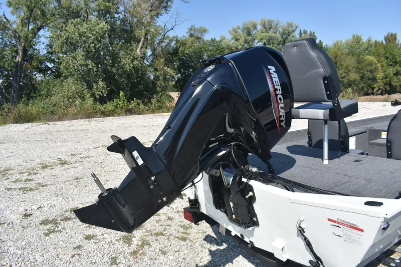 Slide: The Image of 2026 Lowe Skorpion 17 boat with Mercury outboard motor, parked on gravel near trees. - 7