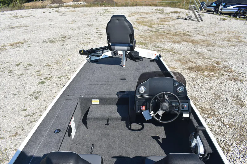 Slide: The Image of 2026 Lowe Skorpion 17 boat interior with steering console and seating on gravel surface. - 8