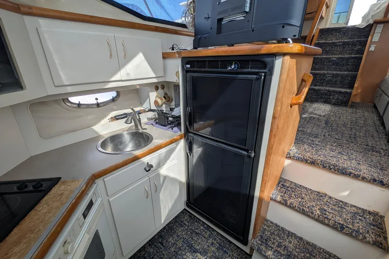 Slide: The Image of 1994 Carver 370 Aft Cabin Motor Yacht kitchen with sink, fridge, and stairs. - 32