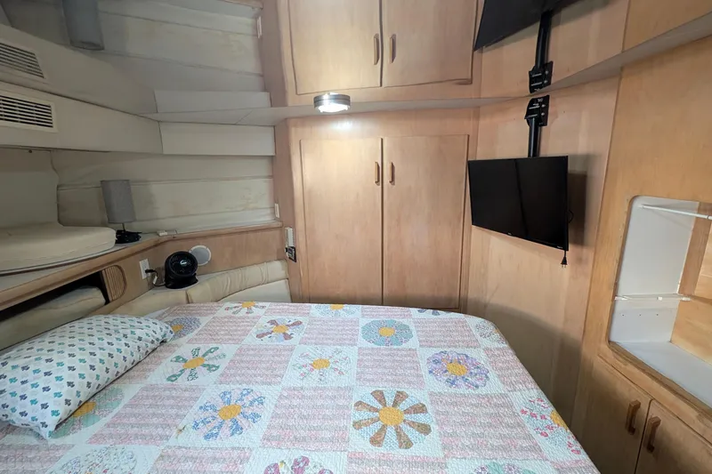 Slide: The Image of 1994 Carver 370 Aft Cabin Motor Yacht bedroom with floral quilt, TV, and wooden cabinets. - 44