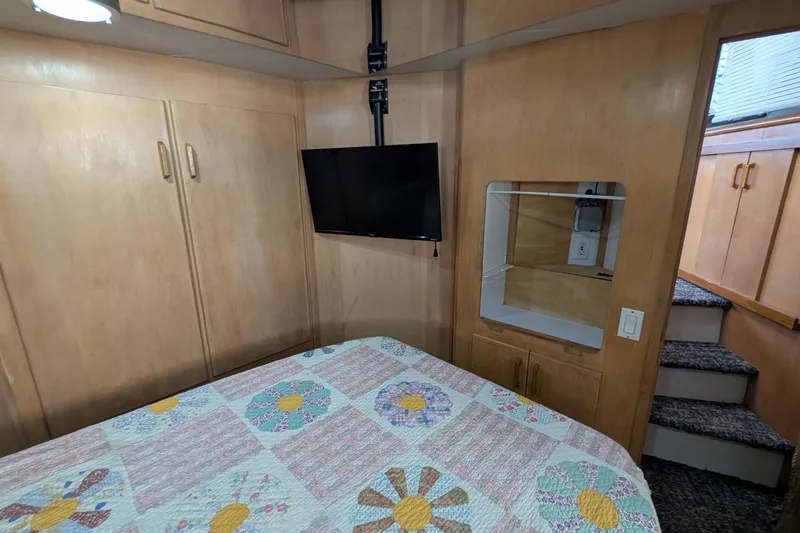 Slide: The Image of 1994 Carver 370 Aft Cabin Motor Yacht interior with TV, quilted bed, and wooden cabinetry. - 43