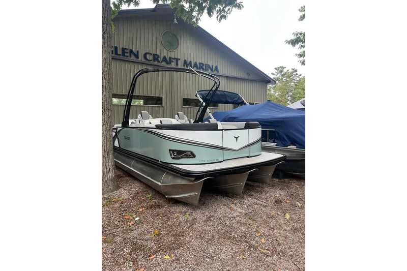 The Image of 2026 Tahoe 23 LTZ Quad Lounger pontoon boat at marina, parked on gravel. - 1