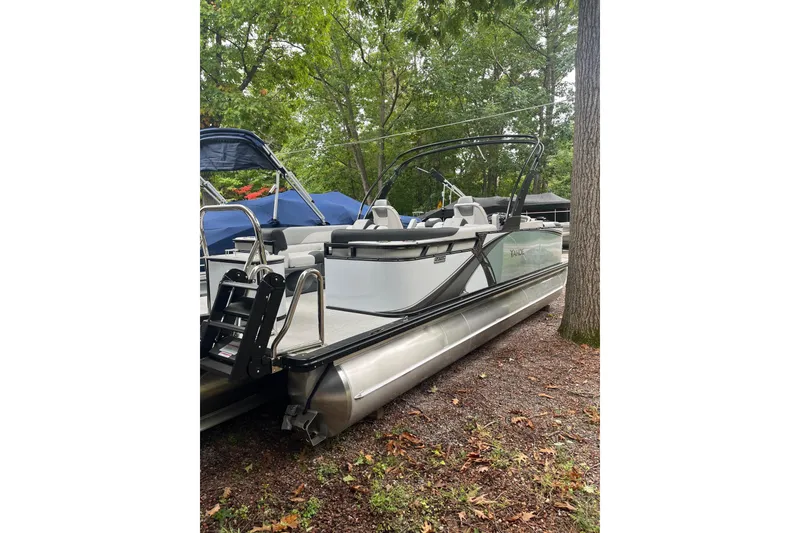 Slide: The Image of 2026 Tahoe 23 LTZ Quad Lounger pontoon boat docked in a wooded area. - 14