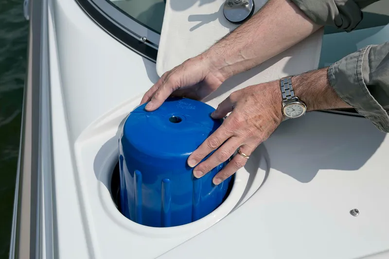 Slide: The Image of Hands placing a blue container on a 2026 Crownline Eclipse E275 boat. - 13