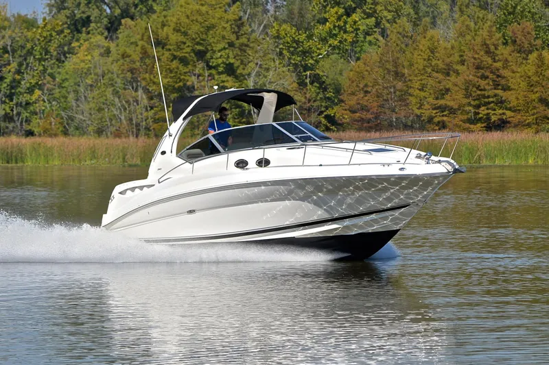 The Image of 2003 Sea Ray 320 Sundancer cruising on a serene lake with lush greenery. - 1