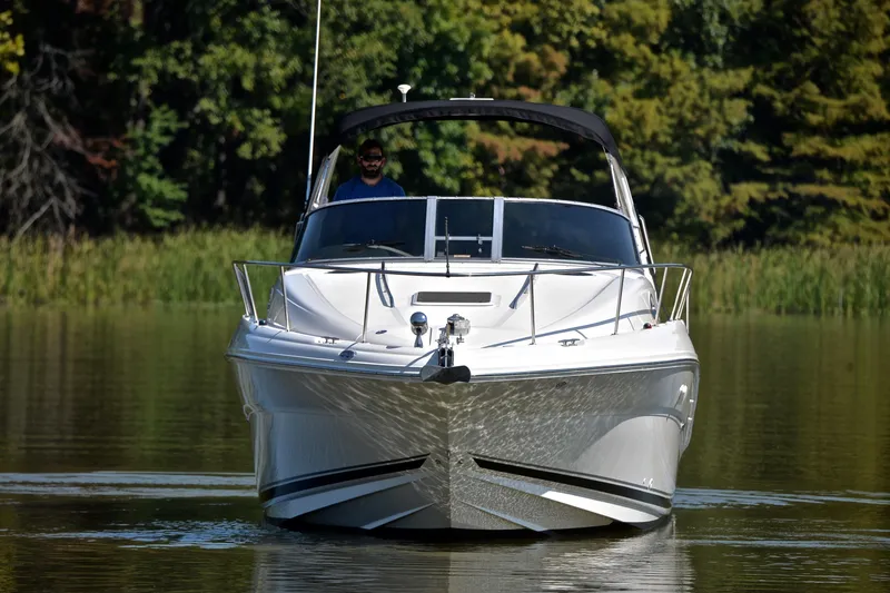 Slide: The Image of 2003 Sea Ray 320 Sundancer cruising on a calm lake with lush green trees. - 11