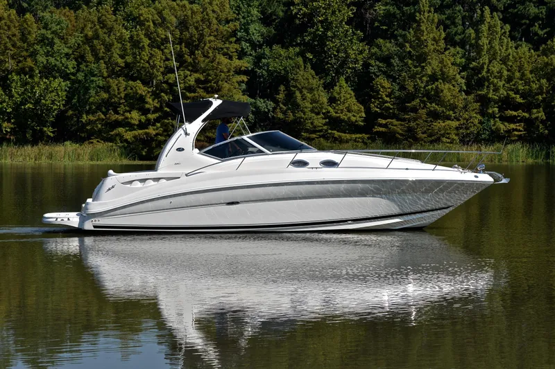Slide: The Image of 2003 Sea Ray 320 Sundancer cruising on a calm lake with lush green trees. - 14