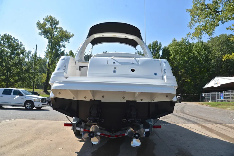 Slide: The Image of 2003 Sea Ray 320 Sundancer boat on trailer, rear view, outdoors with trees and vehicles. - 18