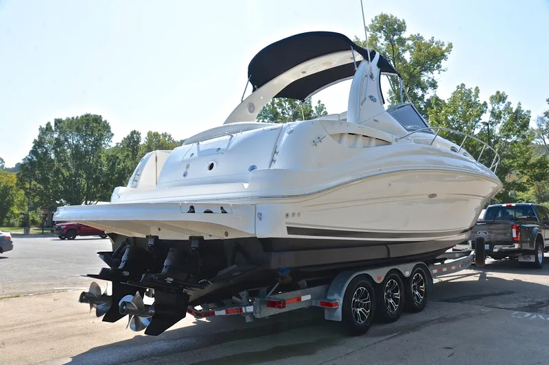 Slide: The Image of 2003 Sea Ray 320 Sundancer boat on trailer, parked outdoors, with trees in the background. - 19