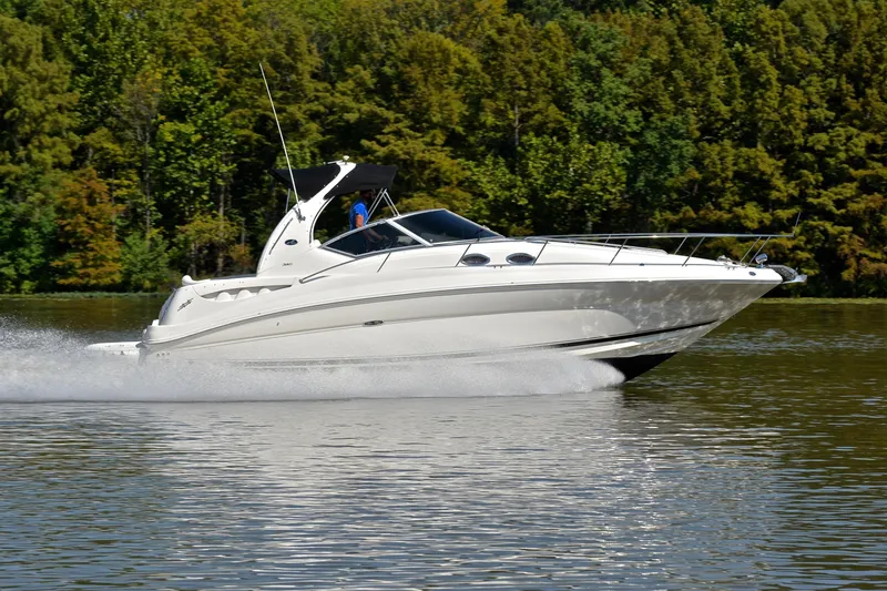 Slide: The Image of 2003 Sea Ray 320 Sundancer cruising on a calm lake with lush green trees. - 3