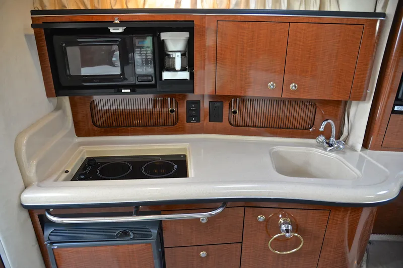 Slide: The Image of 2003 Sea Ray 320 Sundancer galley with microwave, stove, sink, and wooden cabinetry. - 39