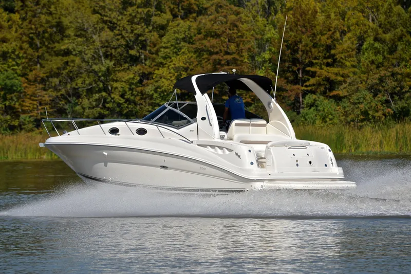 Slide: The Image of 2003 Sea Ray 320 Sundancer cruising on a serene lake with lush green background. - 4