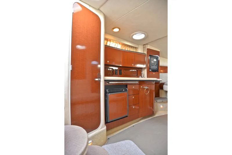 Slide: The Image of 2003 Sea Ray 320 Sundancer interior with wood cabinetry and compact kitchen amenities. - 56