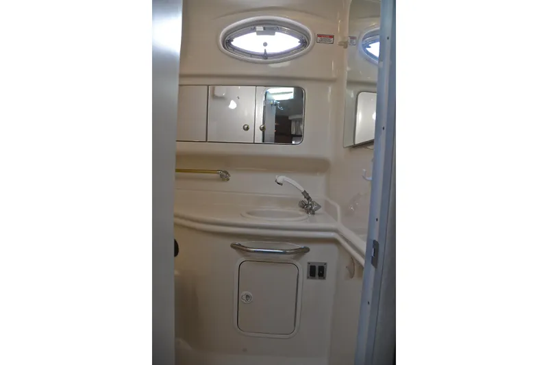 Slide: The Image of 2003 Sea Ray 320 Sundancer bathroom interior with sink, mirror, and storage cabinets. - 58