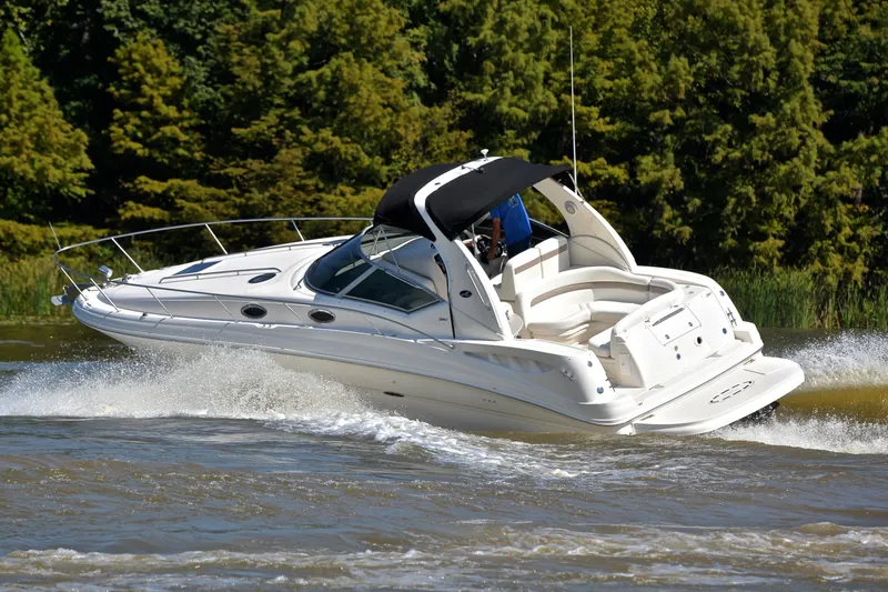 Slide: The Image of 2003 Sea Ray 320 Sundancer cruising on a lake with lush green trees in the background. - 6