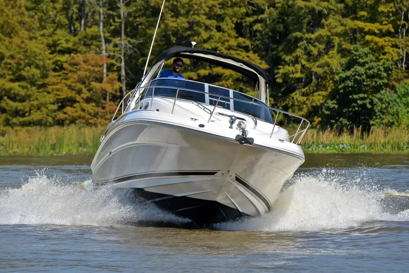 Slide: The Image of 2003 Sea Ray 320 Sundancer cruising on a scenic waterway with lush greenery. - 7