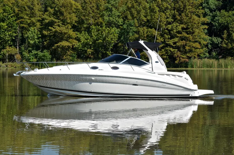 Slide: The Image of 2003 Sea Ray 320 Sundancer cruising on a calm lake with forest backdrop. - 8