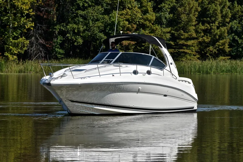 Slide: The Image of 2003 Sea Ray 320 Sundancer cruising on a calm lake with lush green trees. - 9