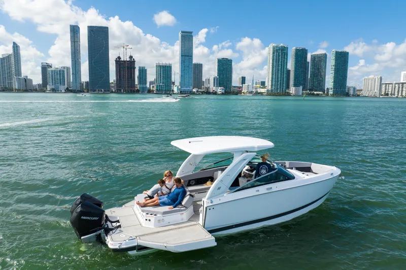 Slide: The Image of 2026 Four Winns H9 OB boat cruising near city skyline on sunny day. - 7