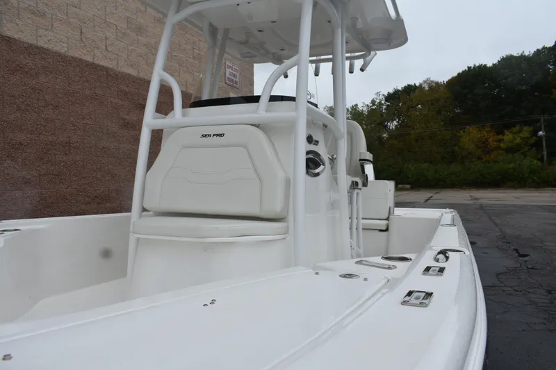 Slide: The Image of 2025 Sea Pro 250 Bay boat, white interior, parked outdoors near brick wall. - 20