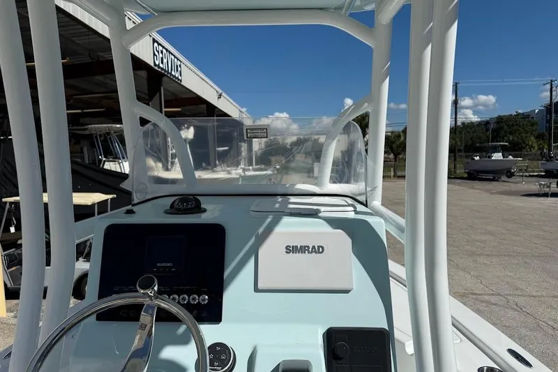 Slide: The Image of 2026 Sea Pro 210 Bay boat dashboard with Simrad display, parked near service area. - 15