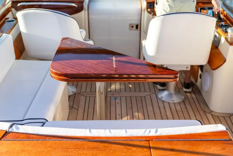 Slide: The Image of Interior of 2005 Hinckley Talaria 29R with elegant wood table and white seating. - 14