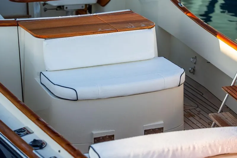Slide: The Image of 2005 Hinckley Talaria 29R boat interior with white cushioned seating and wooden accents. - 24