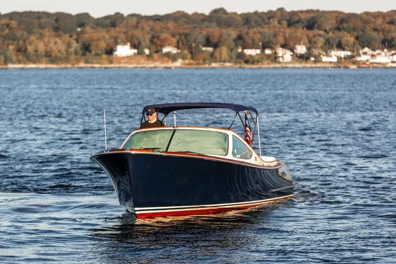 Slide: The Image of 2005 Hinckley Talaria 29R cruising on a serene lake with autumn foliage backdrop. - 7