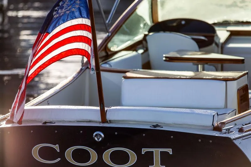 Slide: The Image of 2005 Hinckley Talaria 29R boat with American flag, elegant interior, and "COOT" nameplate. - 10