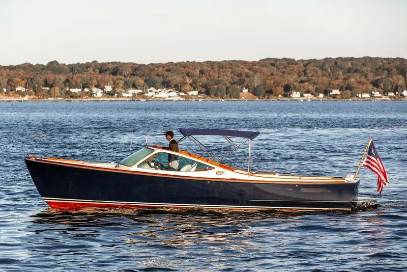 Slide: The Image of 2005 Hinckley Talaria 29R boat cruising on a scenic lake with autumn foliage. - 3