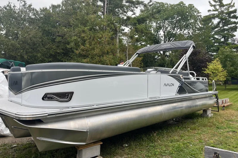 The Image of 2026 Avalon 25 LSZ Elite pontoon boat on grass, surrounded by trees. - 1