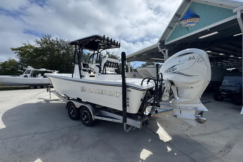 Slide: The Image of 2021 Blazer Bay 2700 Hybrid boat with Yamaha engine on trailer, parked outdoors. - 14