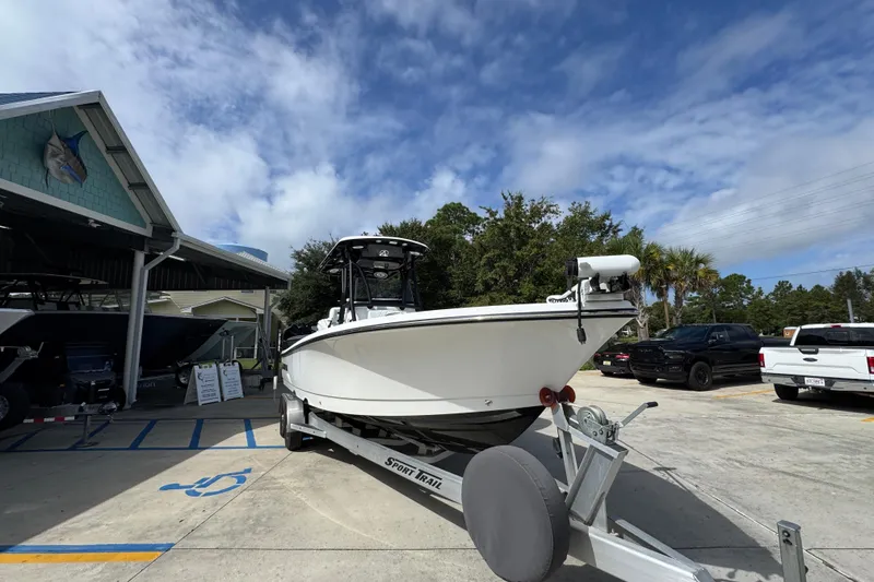 Slide: The Image of 2021 Blazer Bay 2700 Hybrid boat on trailer at dealership under cloudy sky. - 6