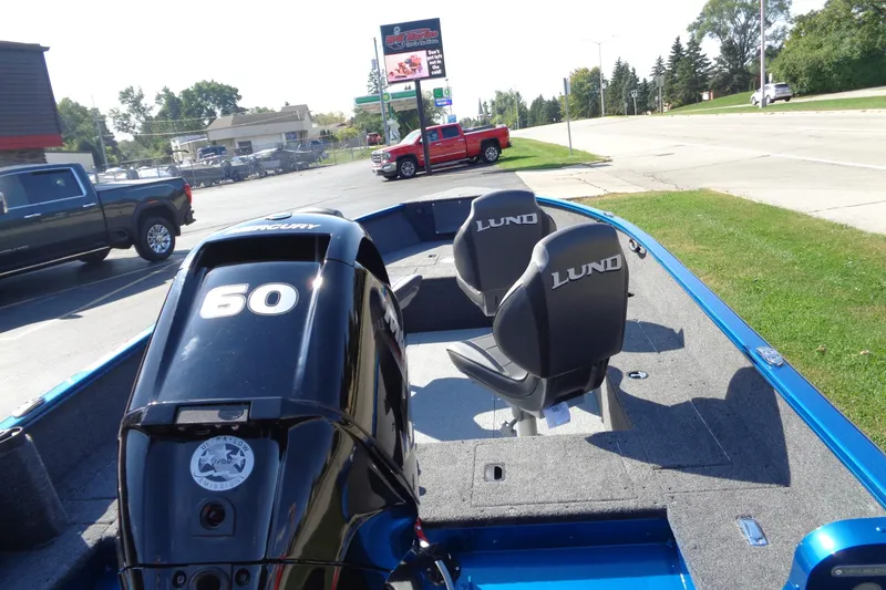 Slide: The Image of 2026 Lund 1650 Rebel Tiller boat with Mercury 60 engine, parked near a road. - 10
