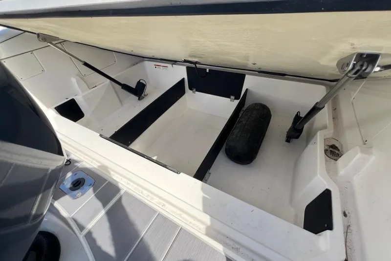 Slide: The Image of Open storage compartment in 2023 Regal LX4 boat, featuring hydraulic supports and a black fender. - 15