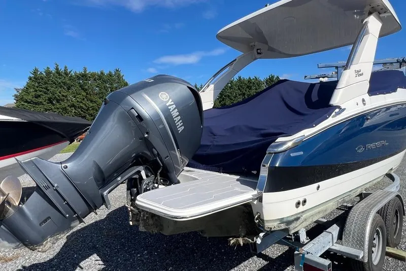 Slide: The Image of 2023 Regal LX4 boat with Yamaha outboard motor on a trailer, covered and parked outdoors. - 8