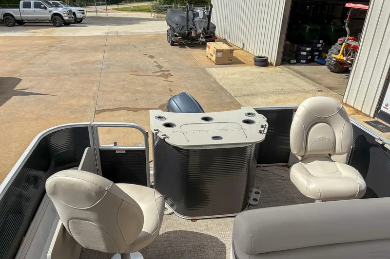 Slide: The Image of 2018 Bennington SX 20 pontoon boat interior with seating and console, parked near a garage. - 13