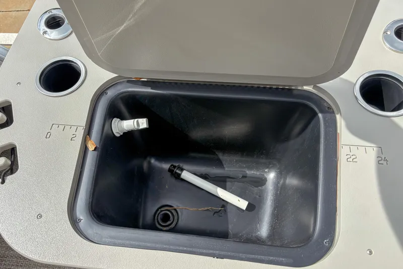 Slide: The Image of Open storage compartment on 2018 Bennington SX 20 boat with cup holders and measuring scale. - 15