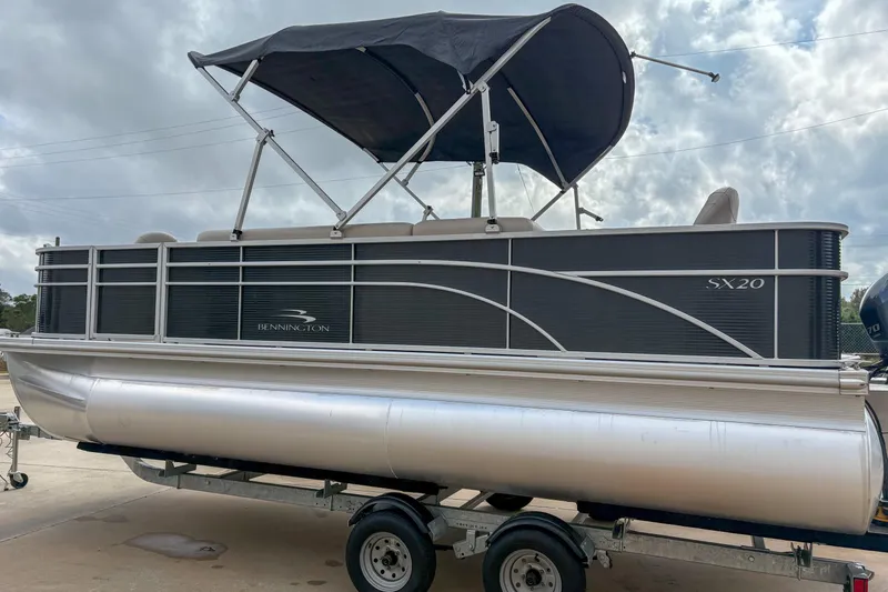 Slide: The Image of 2018 Bennington SX 20 pontoon boat with canopy on trailer, under cloudy sky. - 5