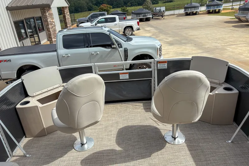 Slide: The Image of 2018 Bennington SX 20 pontoon boat interior with two swivel seats, parked near trucks. - 6