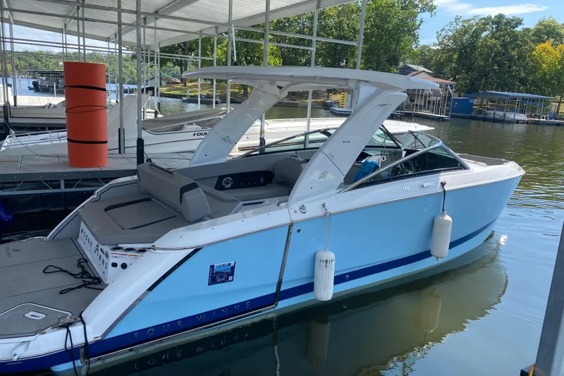 Slide: The Image of 2025 Four Winns H9 boat docked in a marina, featuring sleek design and modern amenities. - 1