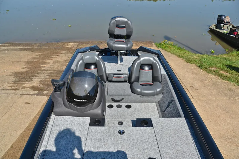 Slide: The Image of 2023 Bass Tracker PRO TEAM 190 boat interior with gray seating, docked by a lake. - 24