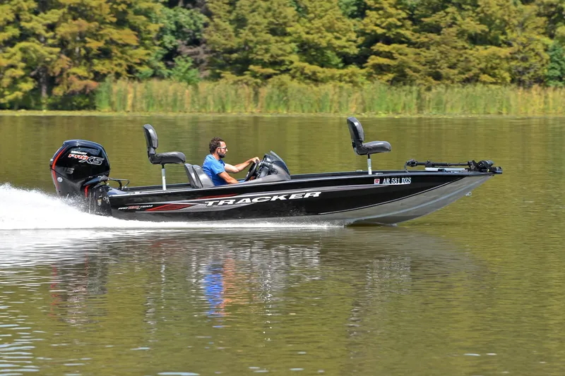 Slide: The Image of 2023 Bass Tracker PRO TEAM 190 boat speeding on a lake with lush green background. - 3